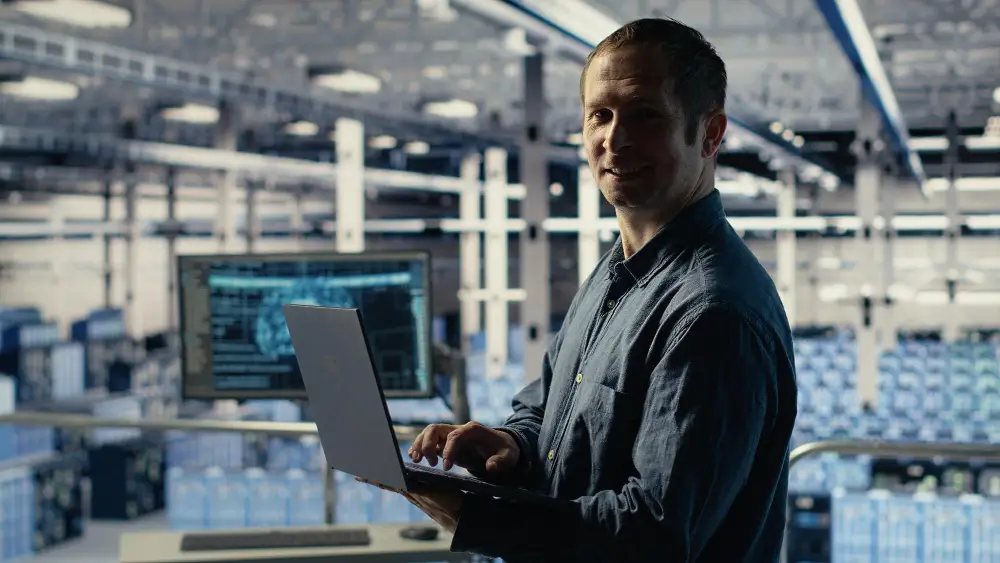 homem com notebook dentro de uma industria simbolizando o sistema web